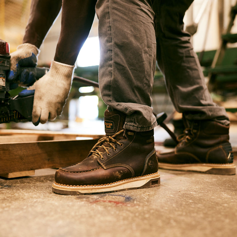 Person wearing brown leather work boots in a workshop setting