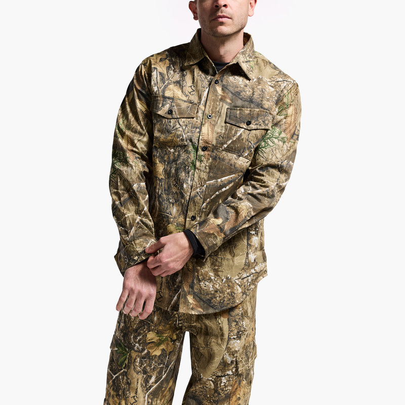 Person wearing a camouflage jacket and pants on a white background