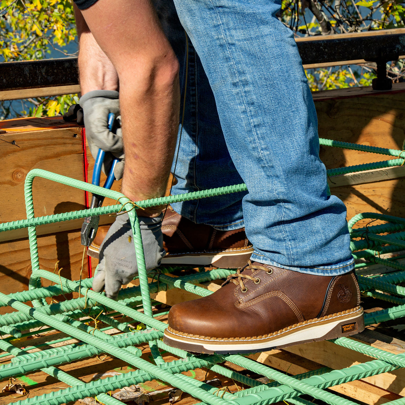 Person wearing brown work boots and blue jeans on a construction site.