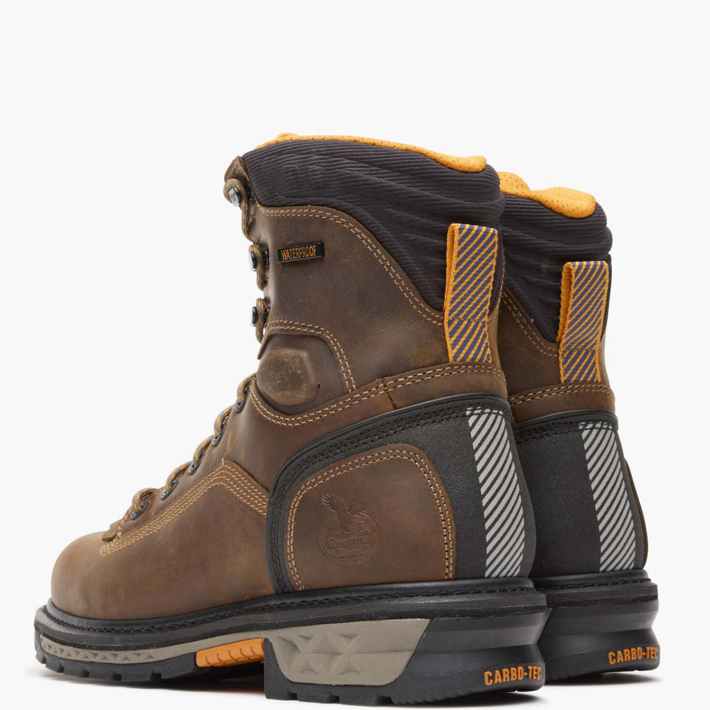 Pair of brown and black work boots with orange accents on a white background