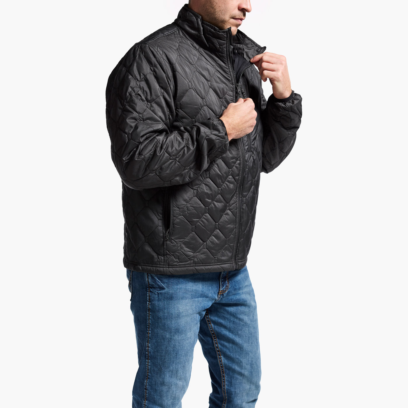 Man wearing a black quilted jacket and blue jeans on a white background