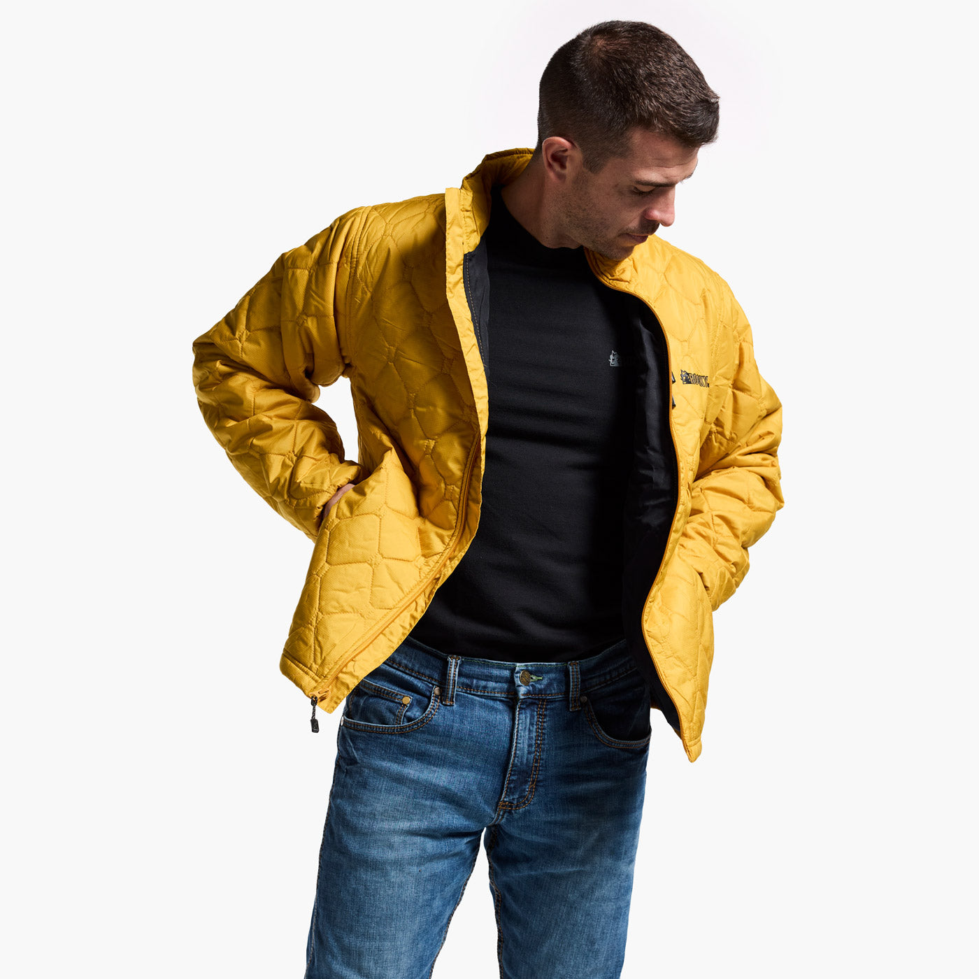 Man wearing a yellow jacket, black shirt, and blue jeans on a white background