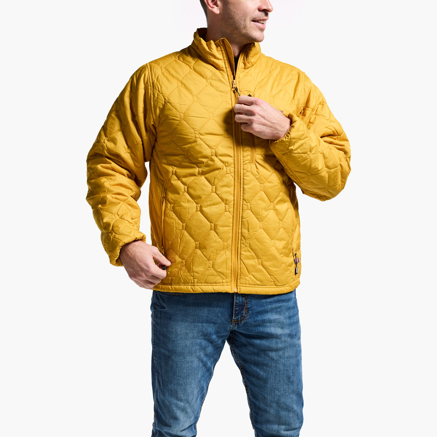 Man wearing a yellow quilted jacket and blue jeans on a white background
