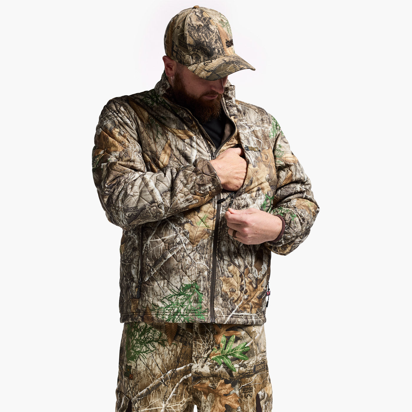 Person wearing a full camouflage outfit with jacket, pants, and hat on a white background