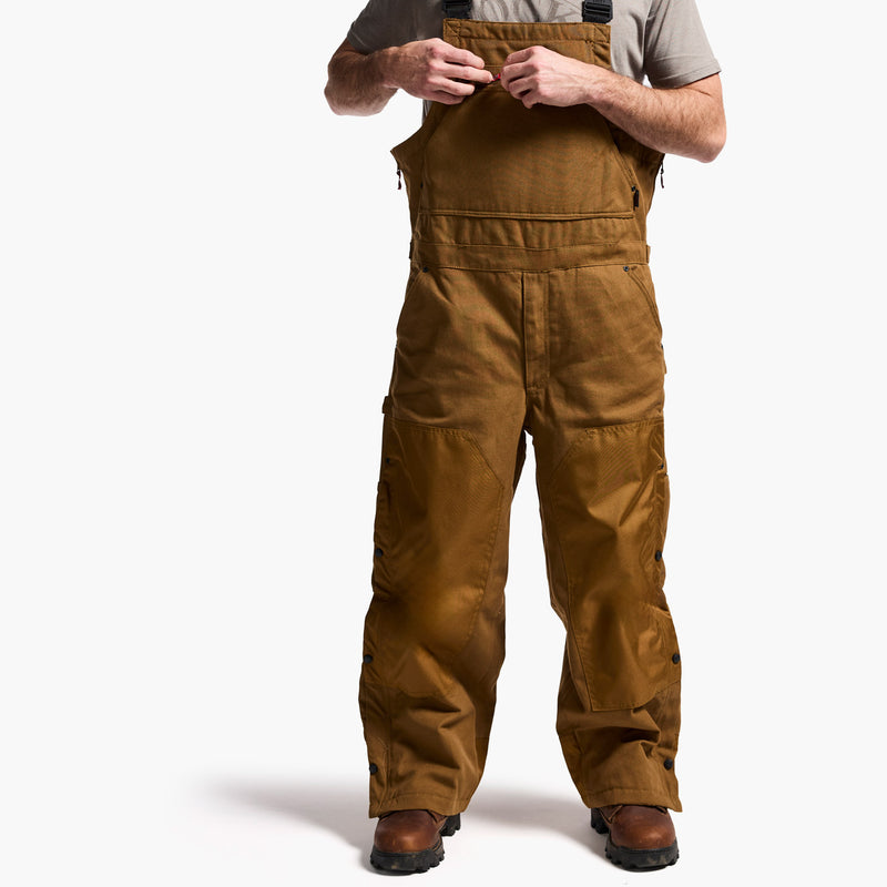 Brown bib overalls worn by a person on a white background